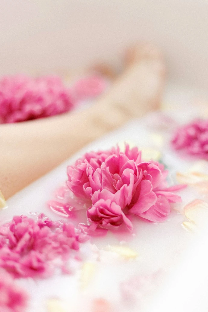 Une personne étendue dans la baignoire remplie de fleurs roses