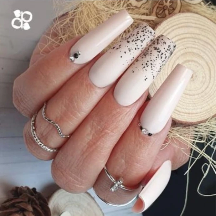 Ongles très longs vernis en rose clair avec des strass